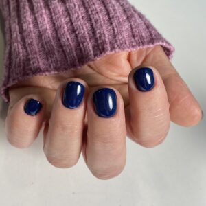 Manicura con esmalte de gel de color azul marino intenso y brillante en uñas cortas y redondeadas, destacando la cobertura y el acabado profesional.